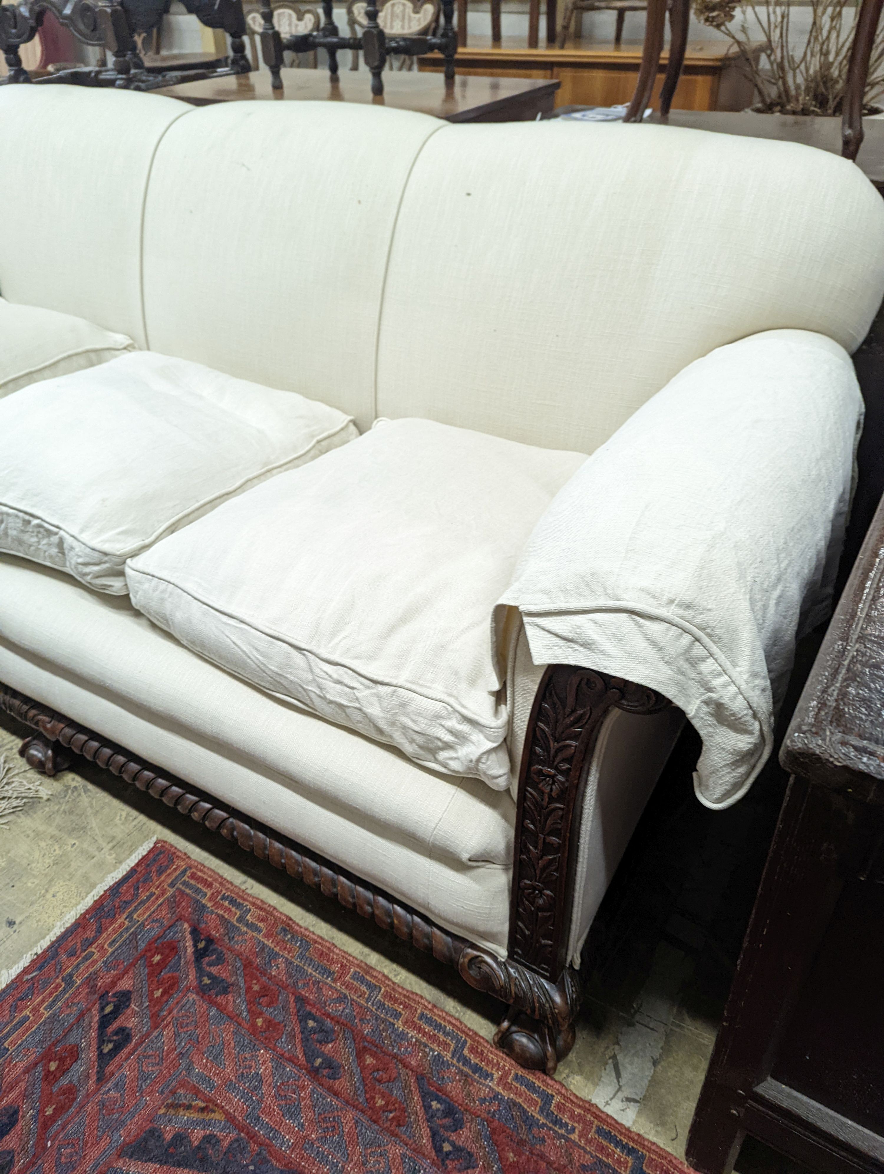 An early 20th century carved mahogany upholstered three piece lounge suite on claw and ball feet, the settee length 194cm, depth 80cm, height 80cm
